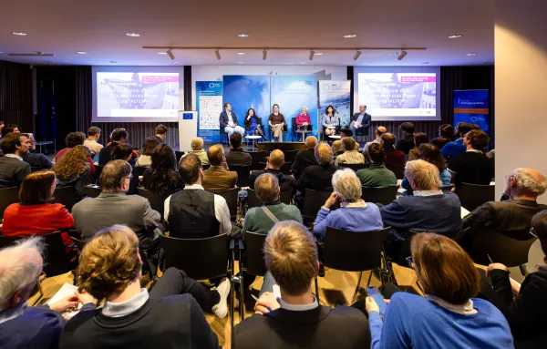Blick auf den gut gefüllten Saal im EU-Infopoint in Berlin auf Publikum und Podium beim 26. Berliner klimagespräch